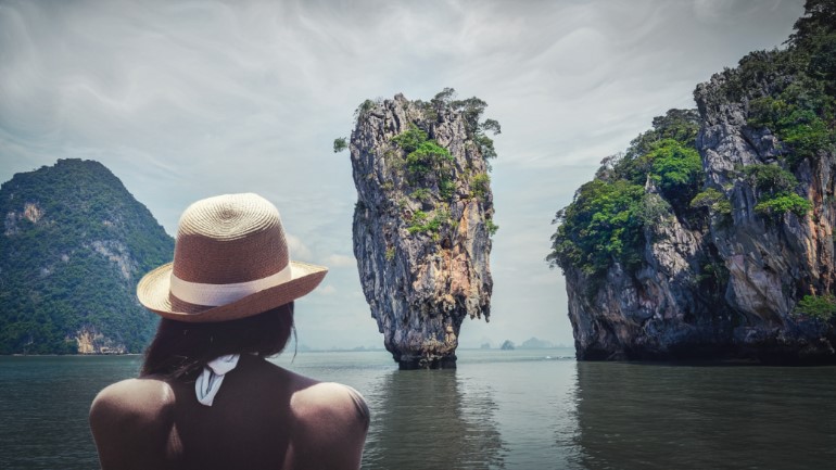 Person staring out at a rock island in the water