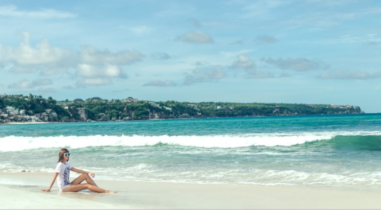 Person staring out to see while relaxing on a beach